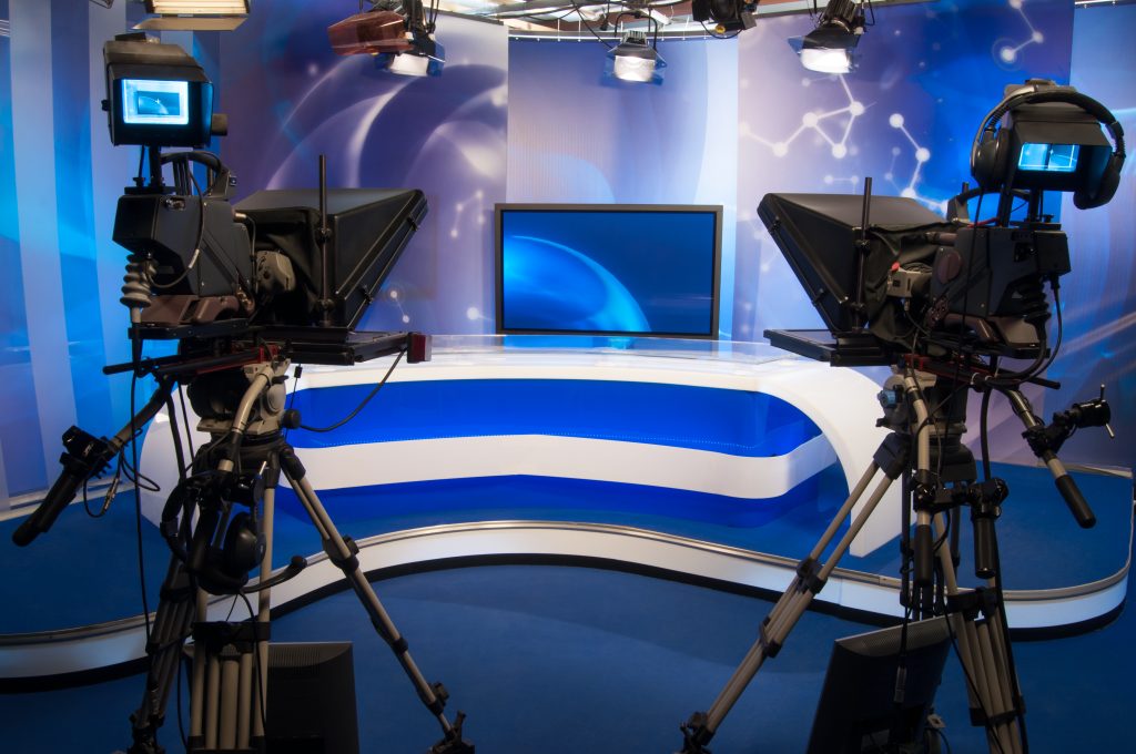 A closeup of modern video cameras on stands in a TV news channel studio